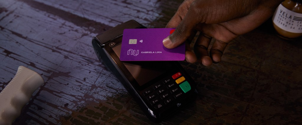 Nubank contactless pedágios: mão aproximando o cartão nubank da maquininha