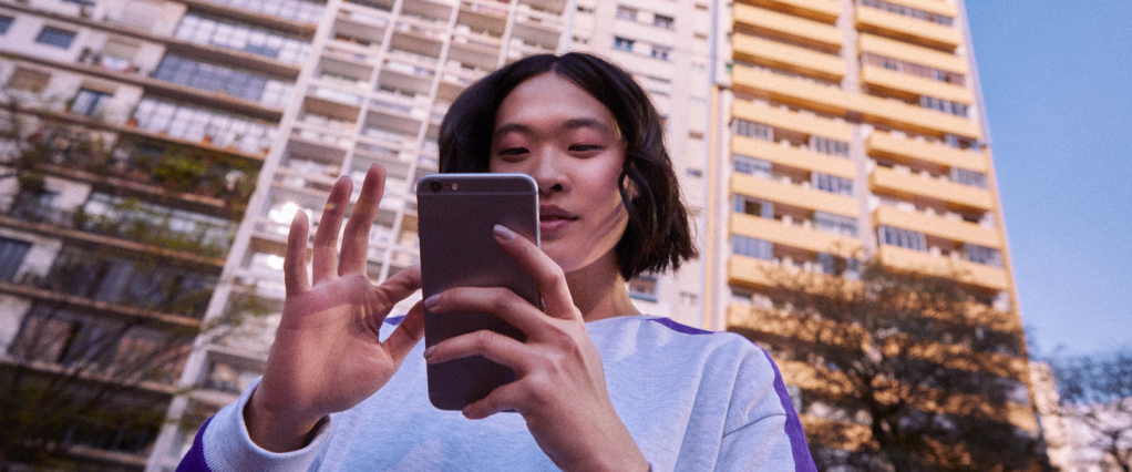 Chaves Pix no Nubank: mulher asiática segurando um celular em frente a um prédio