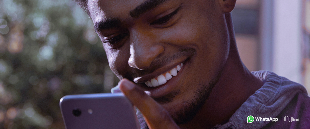 WhatsApp Pay Pagamentos: fotografia de um homem olhando para a tela do celular e sorrindo