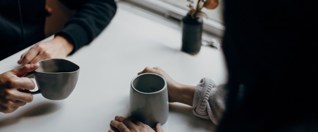 soft skills: uma mulher e um homem conversando enquanto tomam café segurando suas xícaras. Foto: Unsplash @Priscilla Du Preez