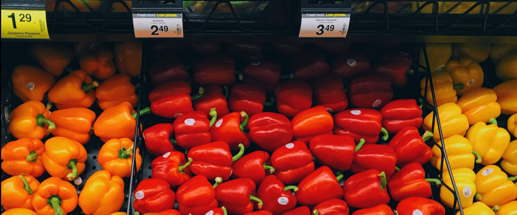 Vender a 0,99 é melhor do que a 1? - Prateleira de supermercado com pimentões amarelos, laranjas e vermelhos. Preços com o número 9 no final. Créditos: Rithika Gopalakrishnan-Unsplash