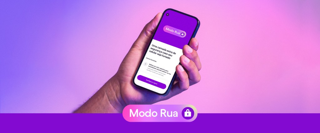 Na imagem, uma mão segura um celular com a tela virada para frente. A tela mostra a função Modo Rua dentro do aplicativo Nubank. A imagem está em um fundo degradé de roxo até rosa, e embaixo está escrito 